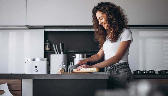 Beautiful woman eating fresh bread at the kitchen