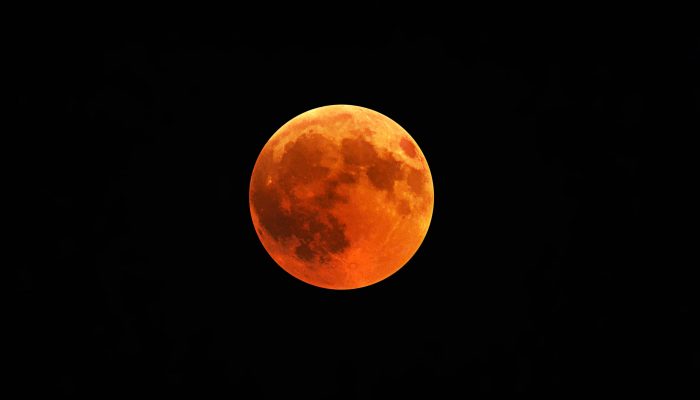 A beautiful shot of a red moon, total lunar eclipse with a black night sky in the background