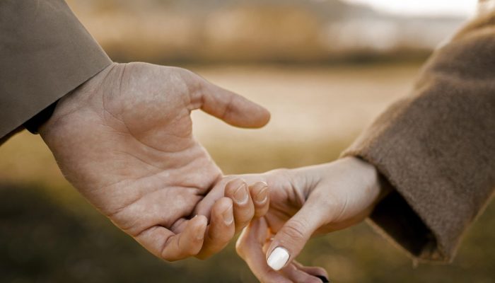 casal-proximo-de-maos-dadas-lado-de-fora