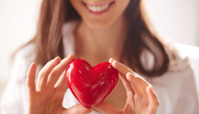 Close-up of smiling female holding red heart