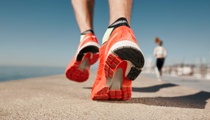 Close up runner feet. Man runner legs and shoes in action on road outdoors at road near sea. Male athlete model.