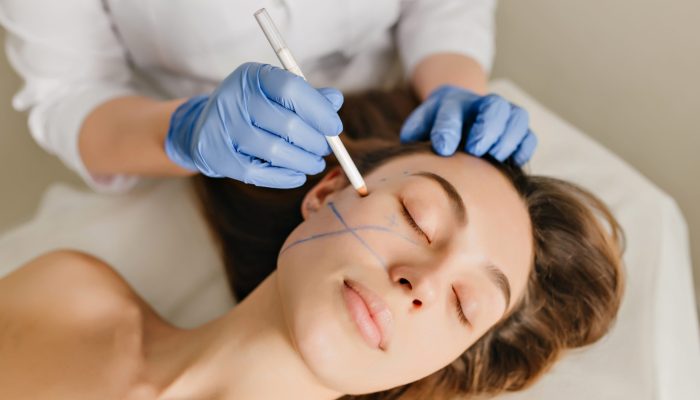 Closeup portrait of beautiful woman during the preparation to cosmetology therapy in beauty salon. Professional dermatology procedures, lifting, rejuvenation