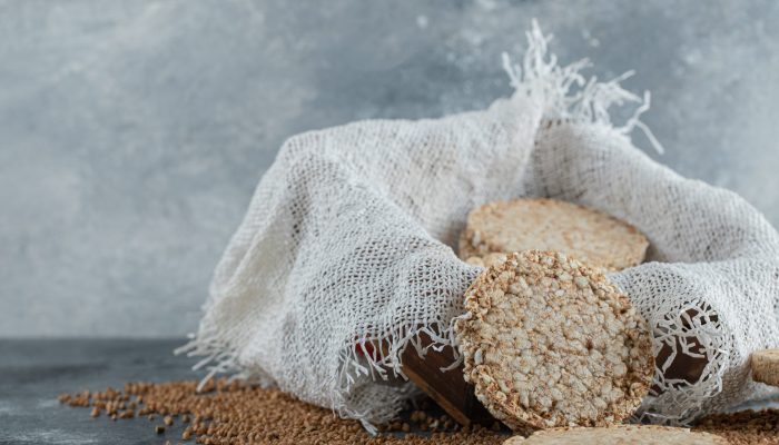 Delicious crispbread and raw buckwheat on marble background. High quality photo
