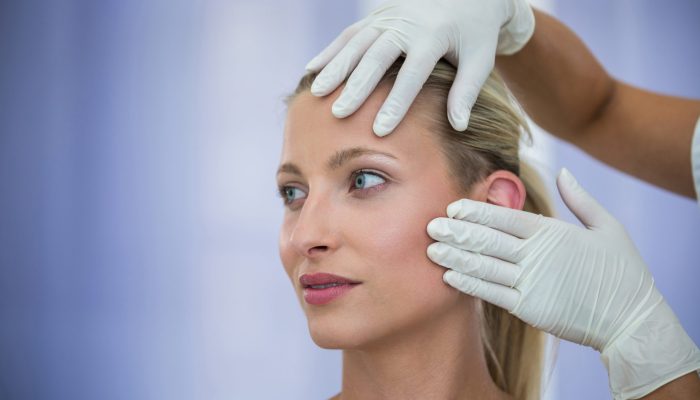Doctor examining female patients face from cosmetic treatment