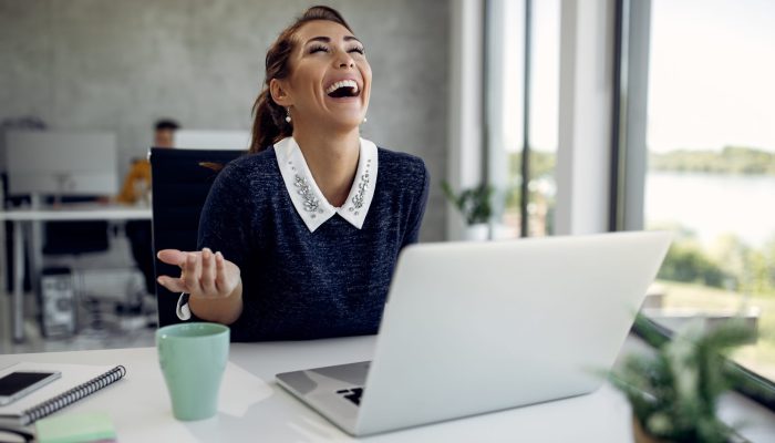 Young happy businesswoman laughing while having video call over laptop in the office.