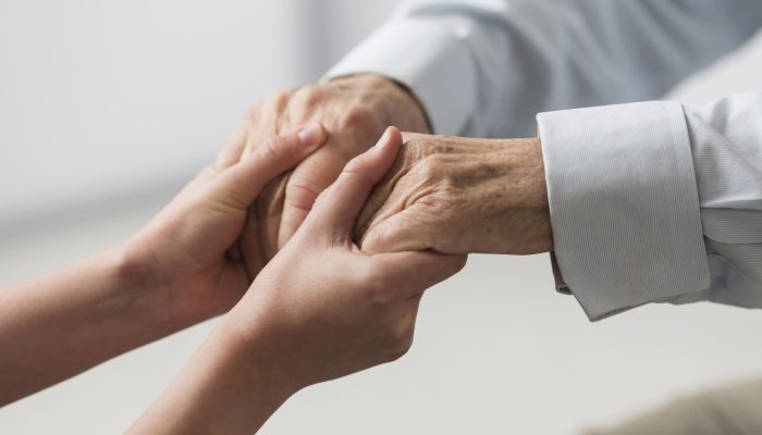 enfermeira-segurando-as-maos-de-um-homem-senior-por-simpatia