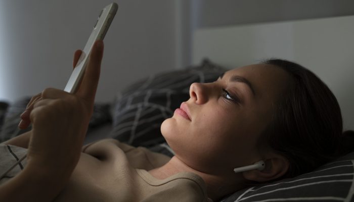 garota-de-vista-lateral-deitada-na-cama-com-smartphone