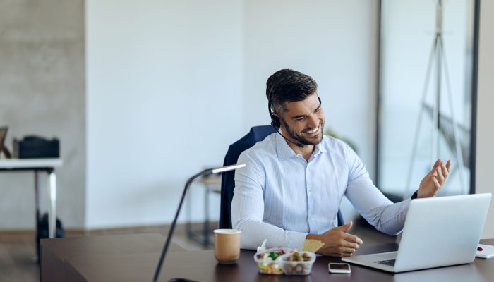 Young happy businessman using computer while having conference call in the office.