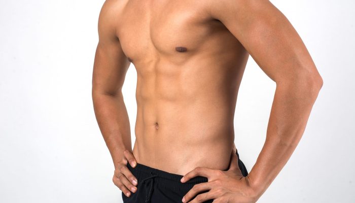 Muscular man showing six pack abs isolated on white background.