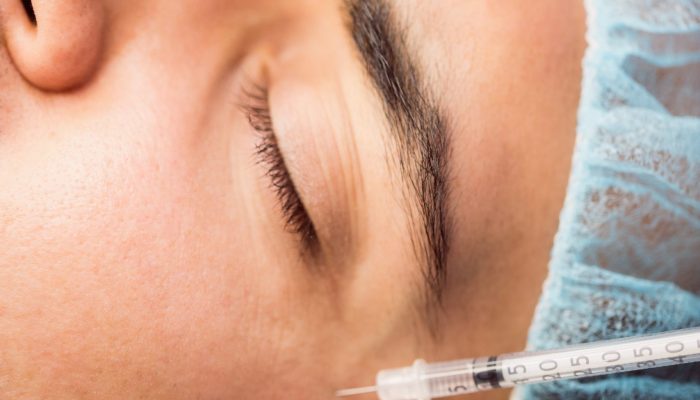Man receiving botox injection on his face at clinic