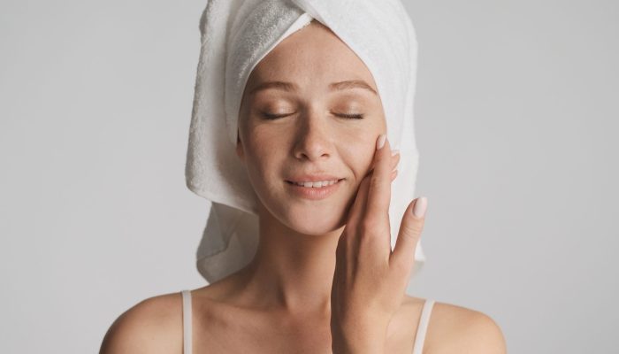 Beautiful girl with smooth healthy skin and towel on head sensually posing on camera isolated. Beauty concept