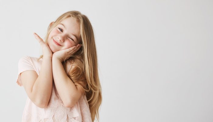 linda-garotinha-loira-sorri-piscando-posando-tocando-o-rosto-com-as-maos-no-vestido-rosa-fofo-crianca-olhando-feliz-e-encantada-copie-o-espaco_176420-10150