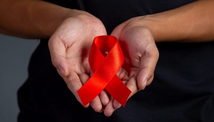 Woman hand holding red ribbon HIV awareness concept World AIDS Day and World Sexual Health Day.