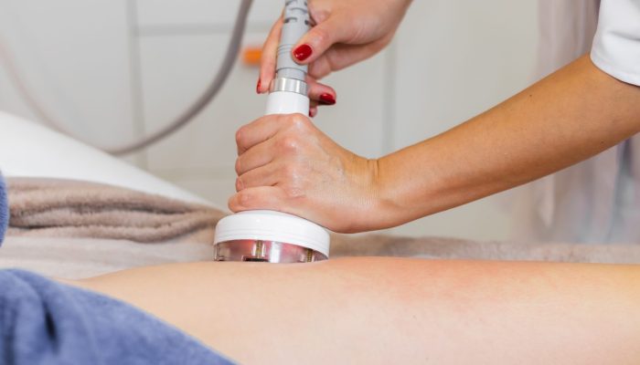 Masseur doing anti-cellulite massage to client in spa beauty salon using oil