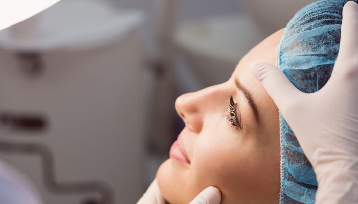 Hands of doctor examining womans face for cosmetic treatment at clinic
