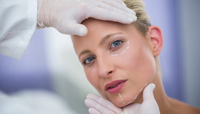 Close-up of doctor examining female patients face for cosmetic treatment