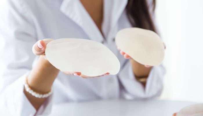 Portrait of female doctor choosing mammary prosthesis in the office.