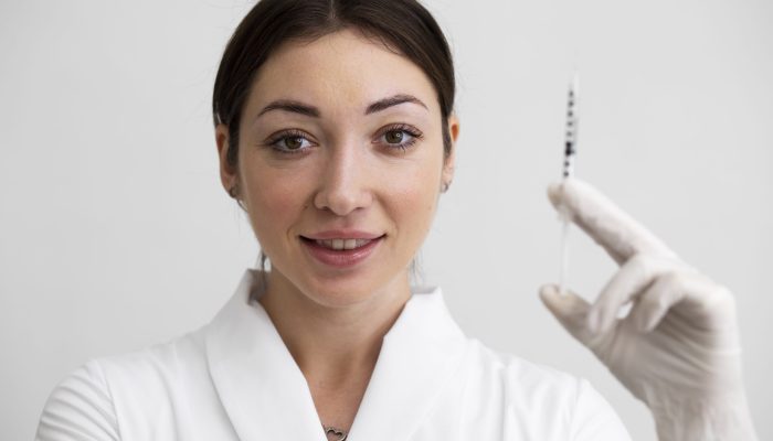 medico-sorridente-de-tiro-medio-segurando-seringa