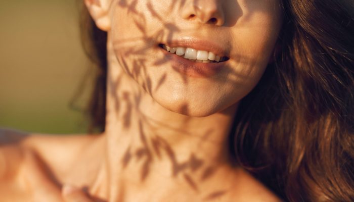 Woman in a summer field. Brunette in a brown sweater. Girl on a sunset background.