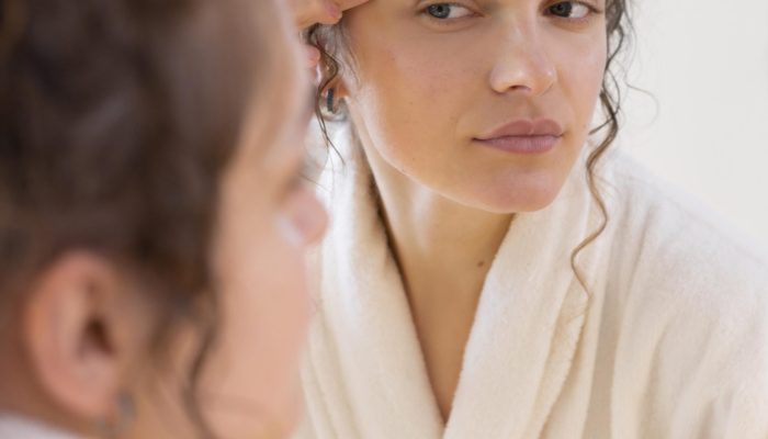mulher-olhando-no-espelho-e-fazendo-uma-rotina-de-beleza-facial-2