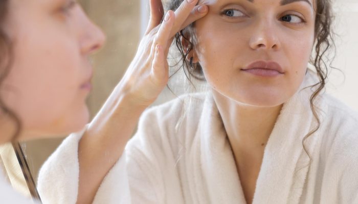 mulher-olhando-no-espelho-e-fazendo-uma-rotina-de-beleza-facial
