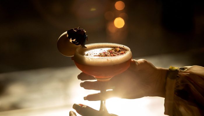 woman holding  a glass of cocktail in sunset