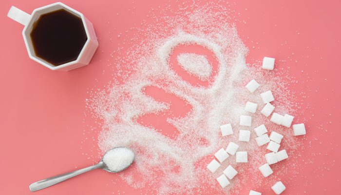 Word No made of sugar and cup of coffee on pink background, flat lay, diabetes problems, harm from eating, dependence on flavoring.
