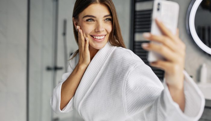 positive-young-woman-bathrobe-taking-selfie