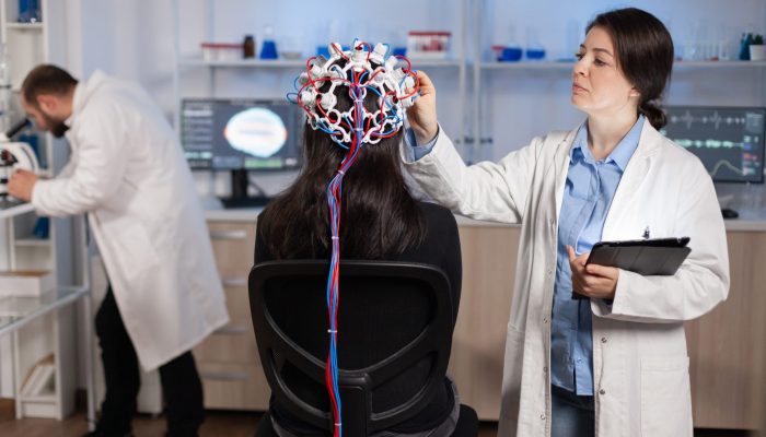 Professional doctor in neuroscience developing treatment for neurological diseases examining patient evolutions. Doctor researcher adjusting EEG headset analyzing brain functions and health status.