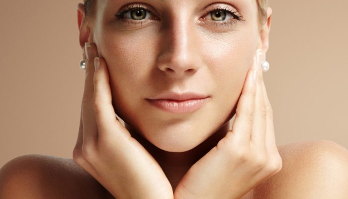 closeup portrait of a woman looking stright at camera and touching her face
