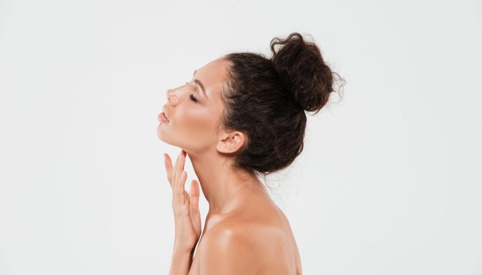 Side view beauty portrait of a sensual young woman with soft healthy skin posing isolated over white background