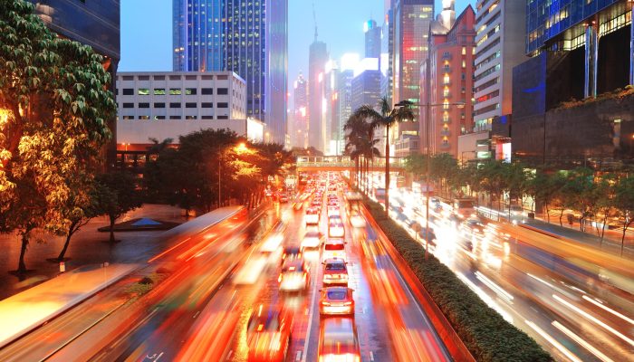 Hong Kong street with busy traffic and skyscraper office at dusk.