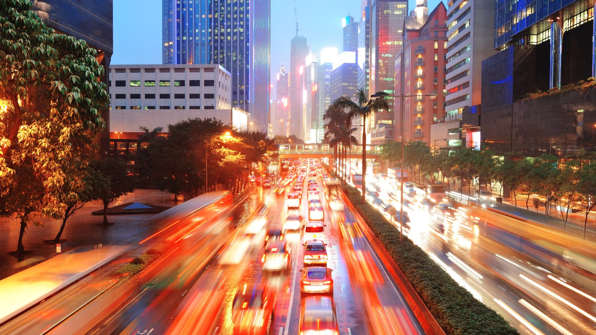 Hong Kong street with busy traffic and skyscraper office at dusk.