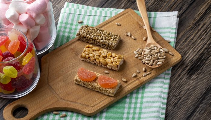 side view of sweet kozinaki of sunflower seeds sesame and peanuts on a wooden board and with marmalade candies in glass jar on rustic background SSUCv3H4sIAAAAAAAACpyRz27DIAzG75P2DhHnRmoG9N+rVDsYwhJUAhWQTVPVd5+BUHHeDf9sf/ZnHu9vXUcEBC3JpXukCGNtzBqih6idRbzfbdwrOyrfEjXq6LwG00IBUc4WFoXQrsYk/MxJEiLENaiQhm1IQlQTahT4kigbXUvc1UROYgemCNk1LKwis4qK+L86y+OzuoFJWfmbF26MeGUUFCPXUkpuP1H5pbUG66hd4+rbSTCpgDZKd6+ltlPT5uKcr1zbpFtt9GmF1+bEOHcHYdKJv1BTVT5DCFg+Vt4MkvinbmnmWBezgU2VjPgTKRzoBx3OR3bgJ04p3x/oVlB+b9aok9epQhjLmx5b6zptQIAzRgXnPeMn0bOT4L1gA/RcnulxYIorOuDhn38AAAD//wMActD1cocCAAA=
