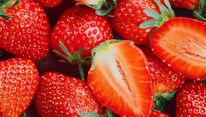 Strawberries cut in half and whole berries, ripe berries top view. Background of ripe strawberries, delicious natural dessert