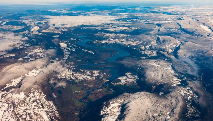 Blue reservoir snaking through snow-covered hills