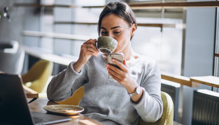 Woman sitting in a cafe drinking coffee and working on a computer